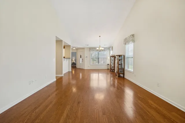 a view of empty room with kitchen and wooden floor