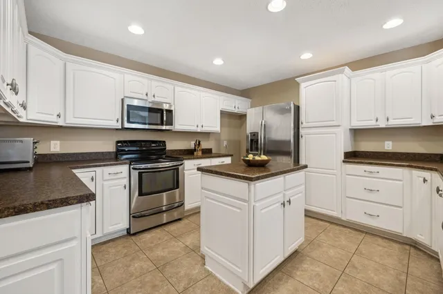 a kitchen with granite countertop white cabinets and white appliances