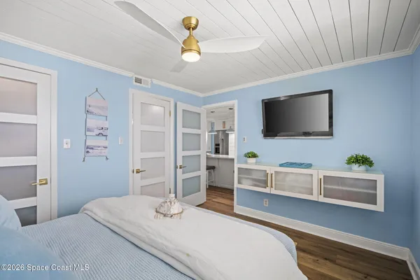a spacious bedroom with a large bed a chandelier and windows