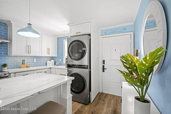 a kitchen with stainless steel appliances granite countertop a refrigerator a sink dishwasher a stove and a dining table with wooden floor
