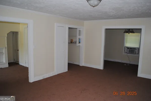 a view of an empty room with closet and a window