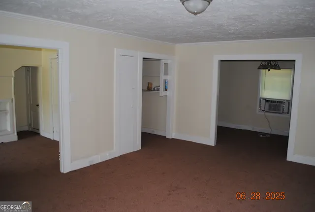a view of an empty room with closet and a window