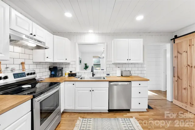 a kitchen with stainless steel appliances a sink a stove a refrigerator and cabinets