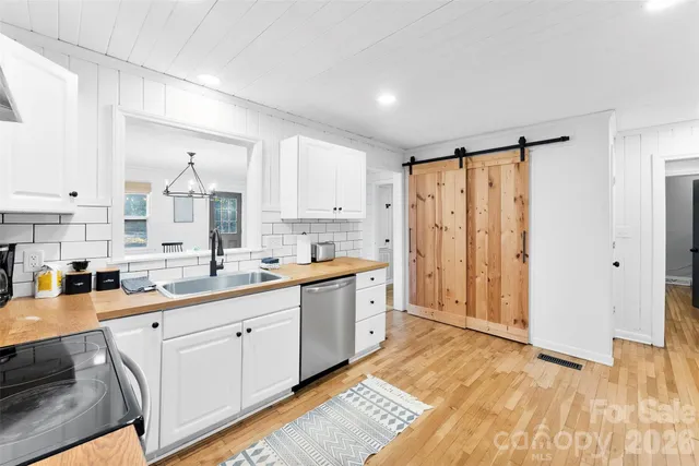 a large white kitchen with granite countertop a sink and cabinets