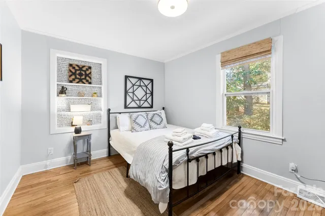 a bedroom with a bed wooden floor and window