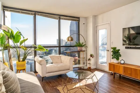 a living room with furniture a flat screen tv and a large window
