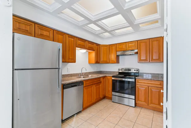 a kitchen with stainless steel appliances granite countertop a refrigerator a sink dishwasher a stove with wooden cabinets