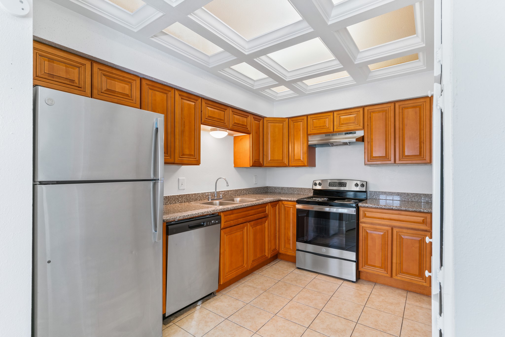 a kitchen with stainless steel appliances granite countertop a refrigerator a sink dishwasher a stove with wooden cabinets