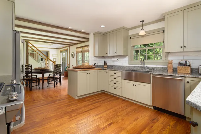 a kitchen with stainless steel appliances granite countertop a sink cabinets and wooden floor