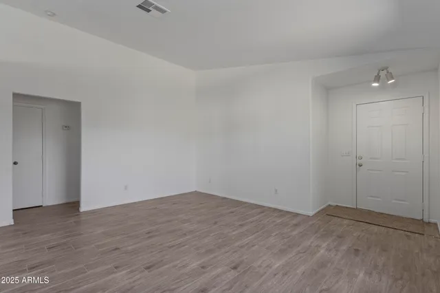 a view of an empty room with wooden floor and a window
