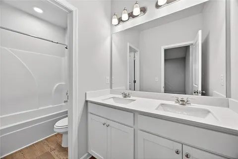 a bathroom with a granite countertop sink a toilet and shower