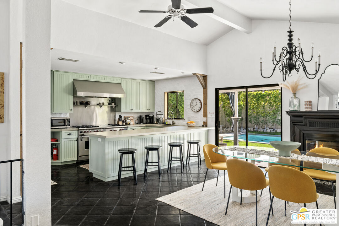 a kitchen with stainless steel appliances granite countertop a table chairs and a chandelier