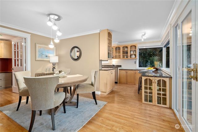 a living room with stainless steel appliances kitchen island granite countertop a stove a sink a dining table and chairs with wooden floor