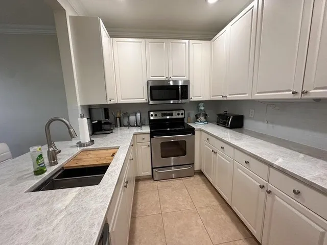 a kitchen with stainless steel appliances granite countertop a stove a sink and white cabinets