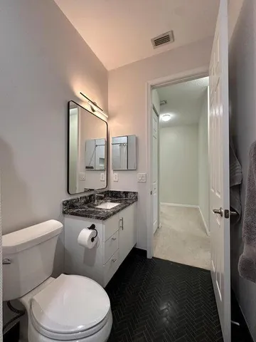 a bathroom with a granite countertop toilet a sink and a mirror