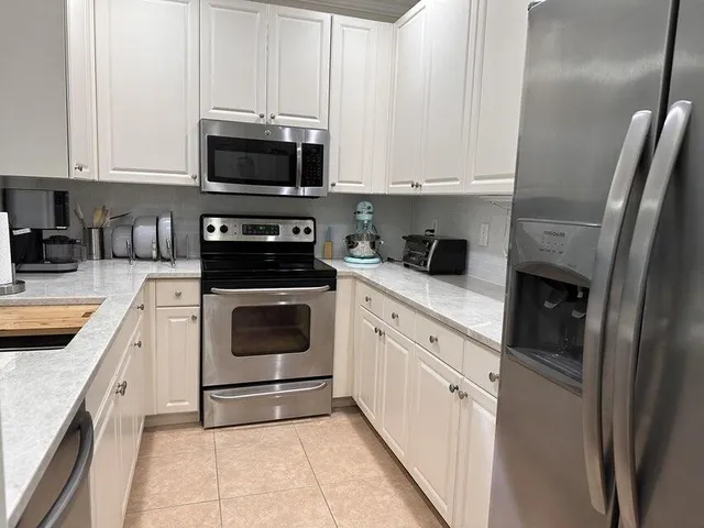 a kitchen with white cabinets and white appliances