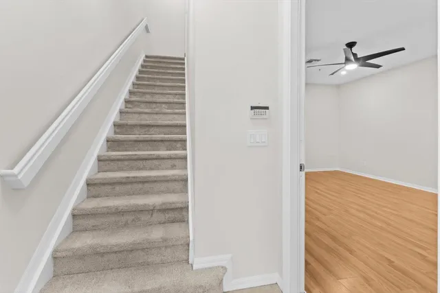 a view of an empty room with wooden floor and a ceiling fan