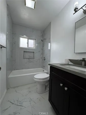 a bathroom with a bathtub sink vanity mirror and toilet