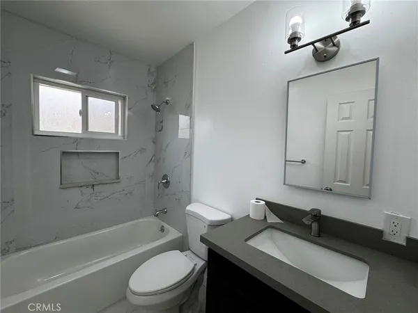 a bathroom with a granite countertop sink toilet a mirror and bathtub