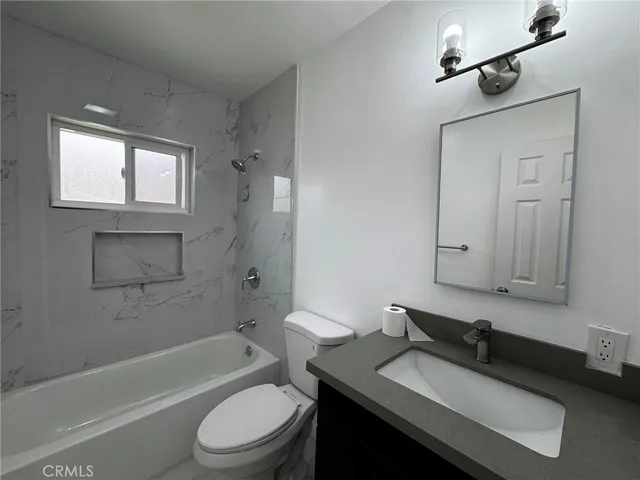 a bathroom with a granite countertop sink toilet a mirror and bathtub