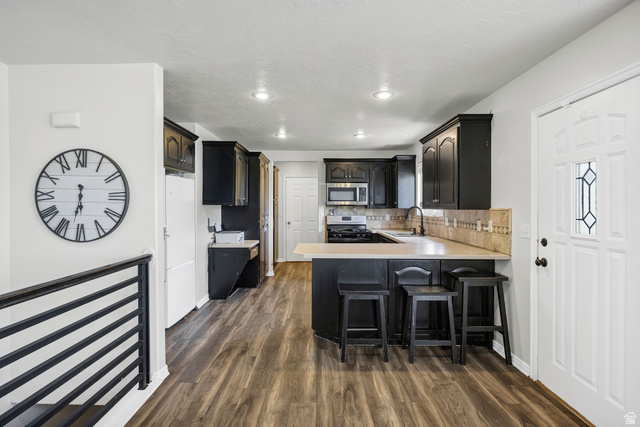892 East 400 South Smithfield, UT 84335 - Photo 9 of 44 Kitchen featuring light countertops, a breakfast bar area, a peninsula, stainless steel appliances, and dark wood finished floors