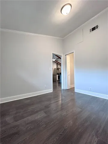 a view of an empty room with wooden floor and closet