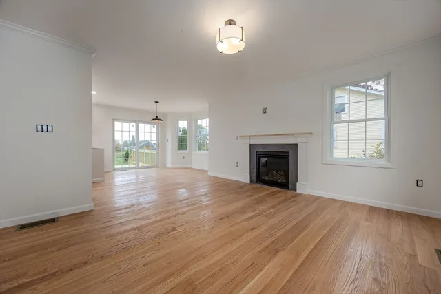 an empty room with wooden floor fireplace and windows