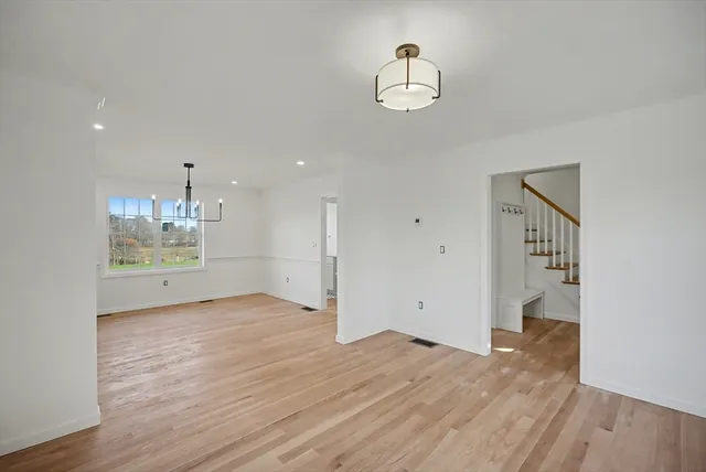 a view of an empty room with wooden floor and chandelier