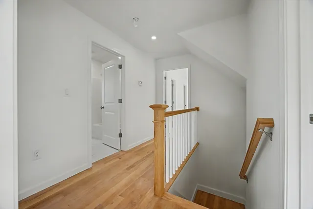 a view of a hallway with wooden floor and staircase