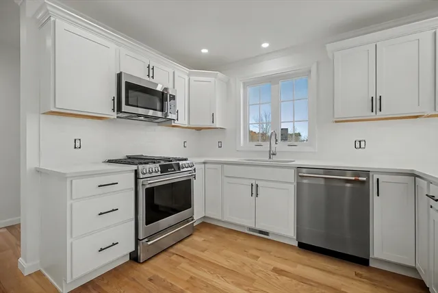 a kitchen with stainless steel appliances white cabinets a sink and a stove
