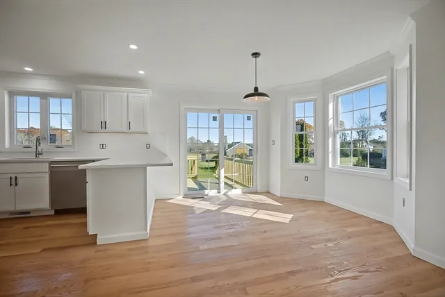 a kitchen with stainless steel appliances granite countertop a stove top oven a sink dishwasher a refrigerator and white cabinets with wooden floor