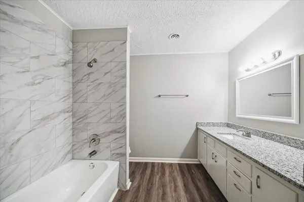 a bathroom with a granite countertop sink a toilet and bathtub