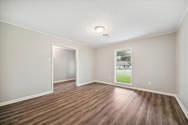 an empty room with wooden floor and windows