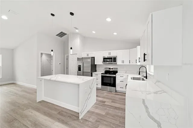 a large white kitchen with stainless steel appliances