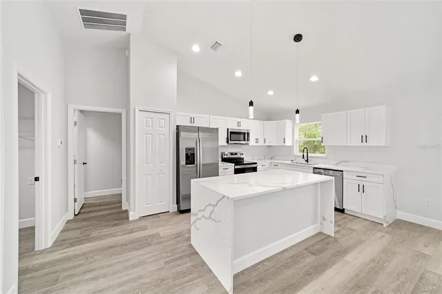 a kitchen with stainless steel appliances a refrigerator sink and white cabinets