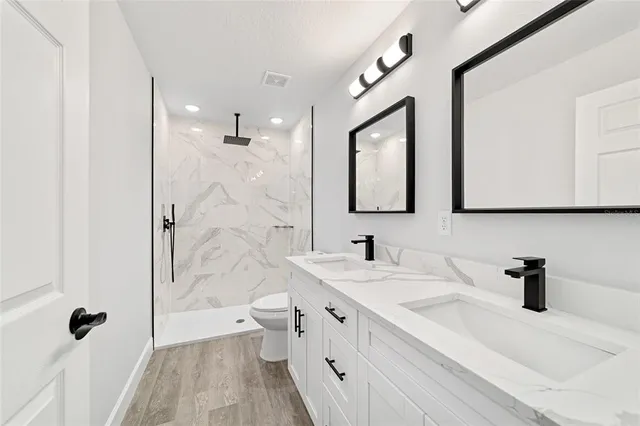 a bathroom with a double vanity sink mirror and shower