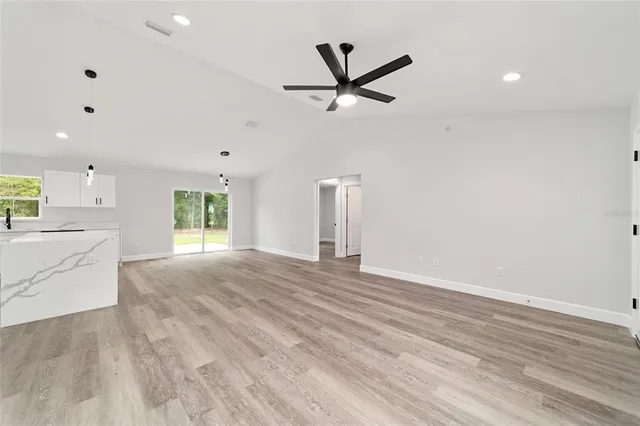 a view of a livingroom with kitchen appliances and a ceiling fan