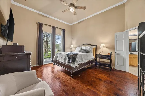 a bedroom with a bed wooden floor and a flat tv screen