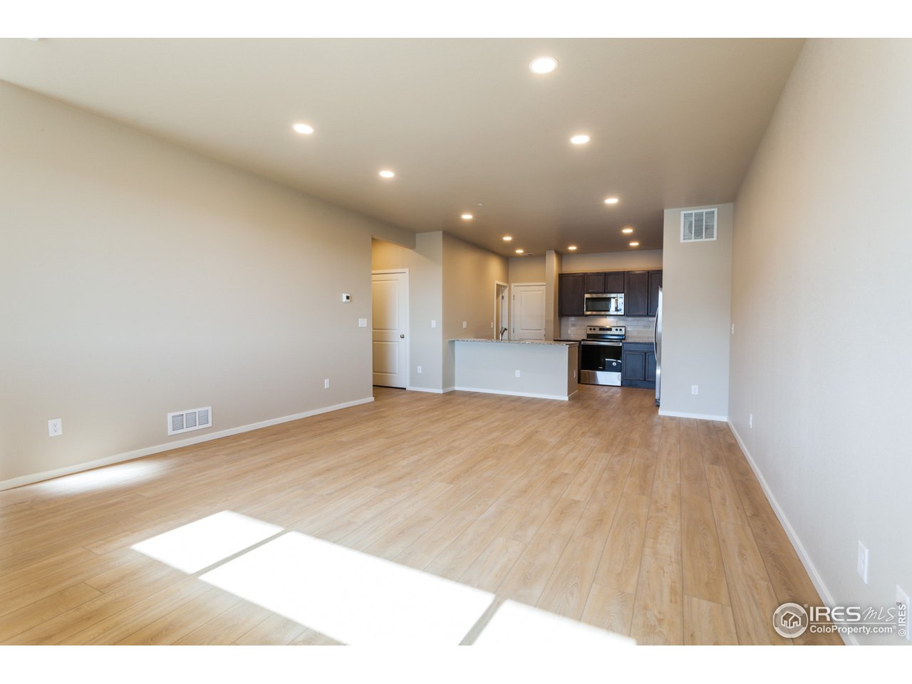 6613 4th St Road, Unit 4 Greeley, CO 80634 - Photo 4 of 34 EXAMPLE PHOTO: LIVING ROOM OPEN TO DINING ROOM & KITCHEN W/ VINYL PLANK FLOORING