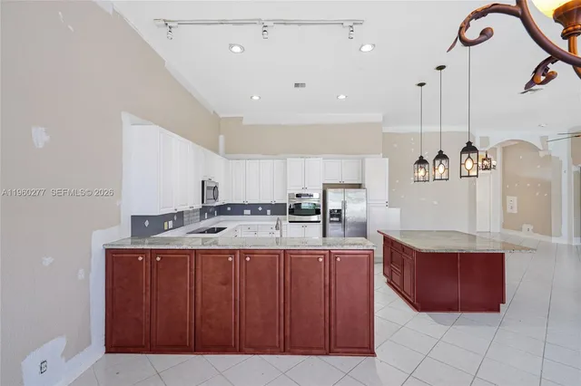 a kitchen with kitchen island granite countertop a sink and a refrigerator