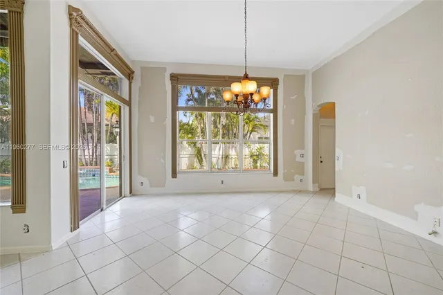 a view of an empty room with window and chandelier fan
