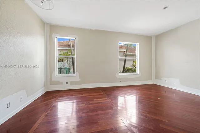 a view of empty room with wooden floor and fan