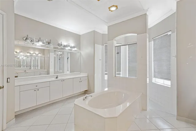 a large white bathroom with a large tub sink and mirror