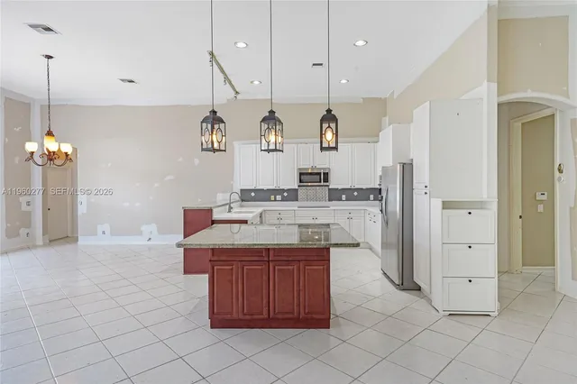 a kitchen with kitchen island granite countertop a sink and a refrigerator