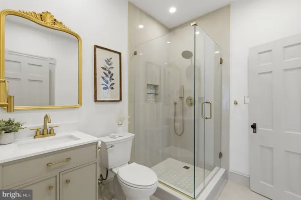 a bathroom with a shower sink vanity mirror and toilet