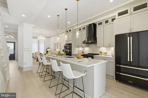 a kitchen with stainless steel appliances granite countertop a refrigerator a stove a sink a dining table and chairs with wooden floor