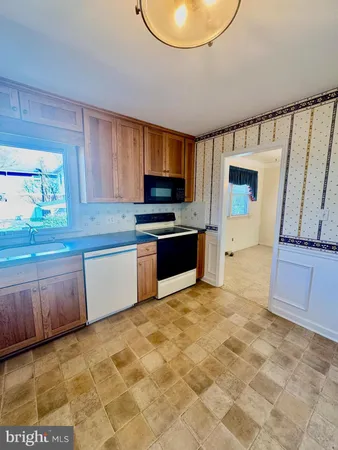 a large kitchen with granite countertop a stove a sink and a microwave