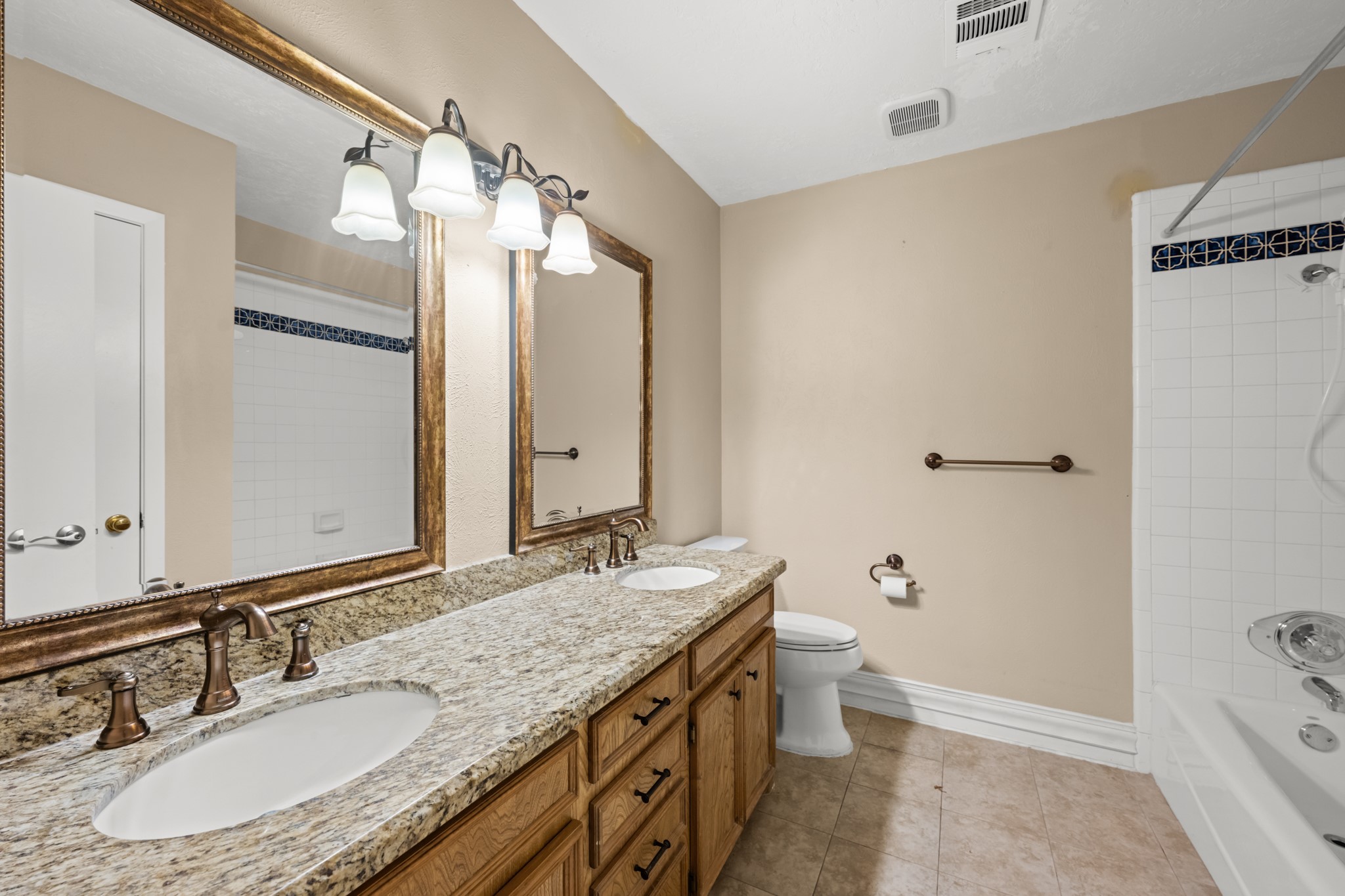 616 Cannan Drive Angleton, TX 77515 - Photo 23 of 49 This well-appointed secondary bath features a granite-topped dual-sink vanity, framed mirrors, and abundant cabinet storage. A tub/shower combination with decorative tile accents provides both style and functionality for family members and guests.