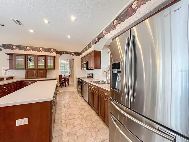 a large kitchen with stainless steel appliances kitchen island granite countertop a refrigerator and a stove top oven