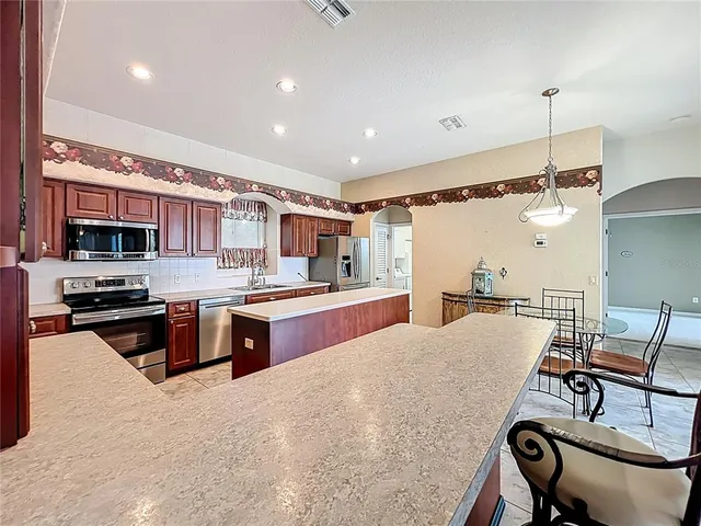 a large kitchen with stainless steel appliances kitchen island granite countertop a sink and cabinets